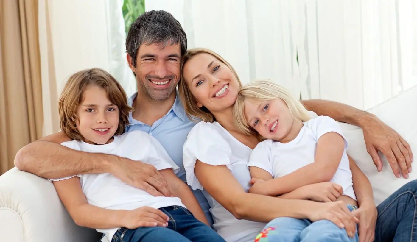 Eine glückliche Familie mit 2 Kindern auf dem Sofa.